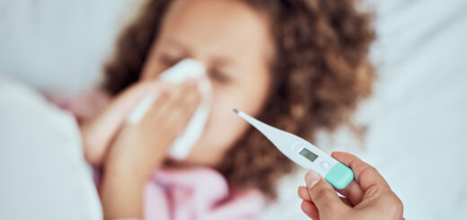 above-mixed-race-little-girl-blowing-her-nose-while-laying-in-bed-feeling-unwell-little-sick-daughter-being-looked-after-her-mother-mom-checking-temperature-of-female-child-who-is-ill-scaled